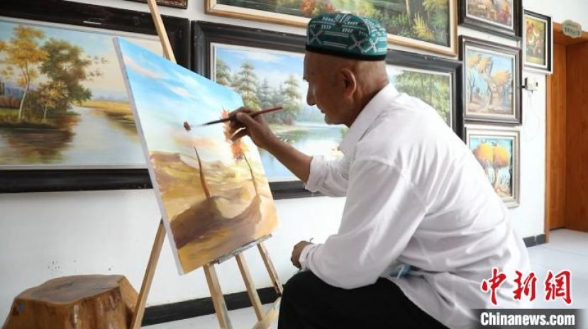 阿卜力克木&middot;麦麦提敏在画一幅关于沙漠胡杨的作品。