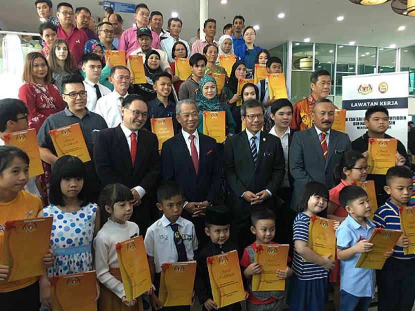 内政部长丹斯里慕尤丁在古晋移交公民权批准函给31人后合影，其左为副贸消部长张健仁。