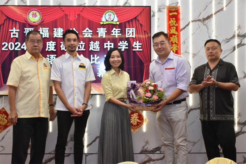 辩论比赛筹委会主席黄冀义（右二）颁发纪念品予砂副总理拿督斯里沈桂贤的代表砂总理署政治秘书许德婉（左三）。左一起为大马福联会副会长暨古晋福建公会监察主席郑文新、古晋福建公会青年团团长暨大马福联青理事黄惟玄。右一为古晋福建公会秘书长甲必丹陈国璋。