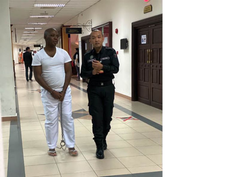 贩卖毒品的尼日利亚青年，也就绞刑判决提出上诉遭驳回后，在新的规则下，双手脚都被铐上铁链，押离法庭时摄。