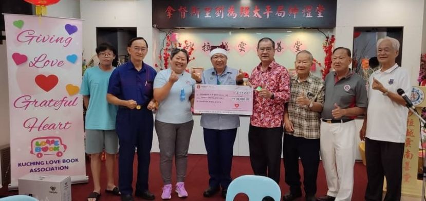 在古晋南市市长黄鸿圣（左四）见证下，古晋爱心书协会主席兼创办人吕晗韵（左三）移交38爱心慈善基金会3万令吉捐款模拟支票予砂拉越云南善堂主席郑文新，左起为Cyrus Loo及砂云南善堂副主席郭兴开；右起为正福利本固鲁田新华、副主席郑瑞福及副主席钟名宝。