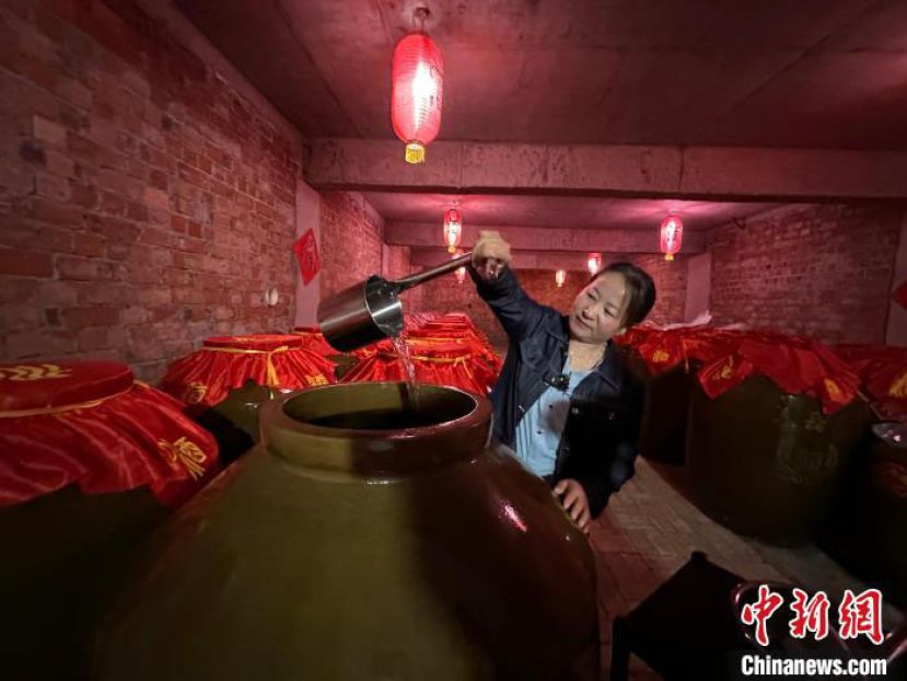 刘艳在自家“庭院式”生态酿酒作坊的酒窖里准备品酒。