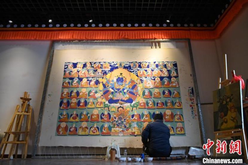甘肃甘南藏族自治州夏河县唐卡小镇，画师旦正嘉席地而坐绘制唐卡。