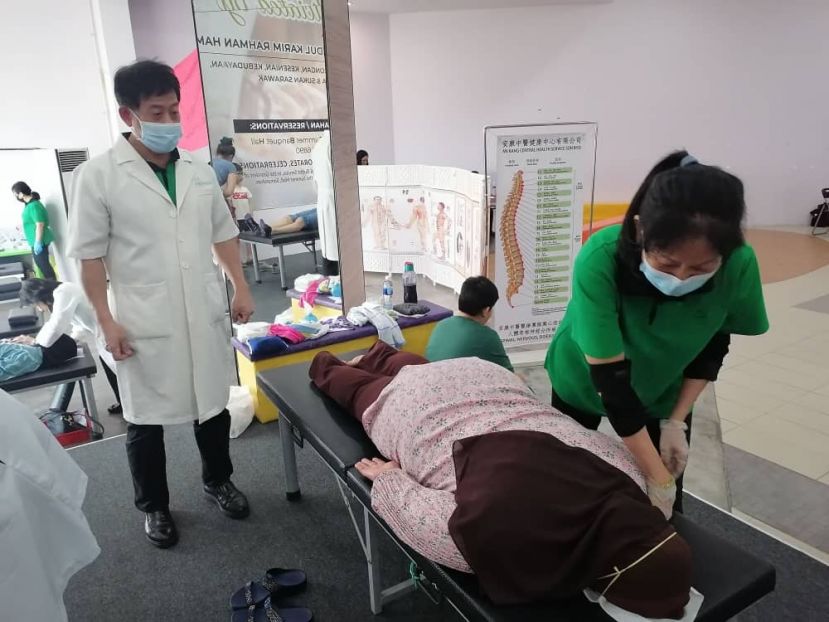 来自台湾名医许国模（左）在义诊上看许爱丽医师为马来妇女中医整骨。