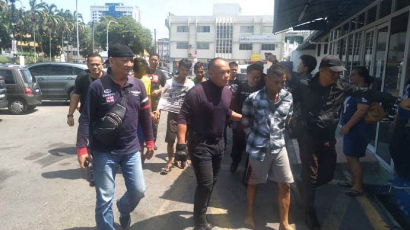 刑警将落网匪徒押返警局查办。