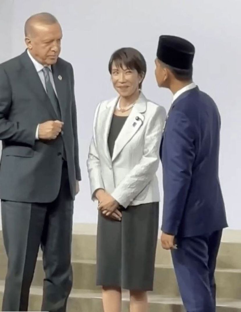 高市站在土耳其总统埃尔多安（左）与印尼副总统拉卡（右）之间，两人正隔着她交谈，身为“夹心位”的高市只能面露尴尬、陪笑硬撑。