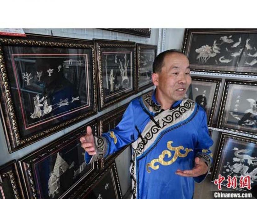 孙玉林在工作室介绍自己的鱼皮画作品《猎归》。