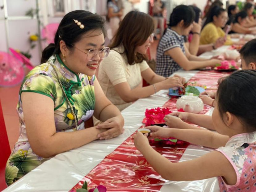 幼儿端茶给妈妈，妈妈露出灿烂的笑容。