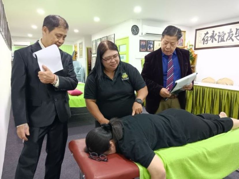 江宗兴院长（右）及考官林友镁为一学员的推拿手法考试打分。