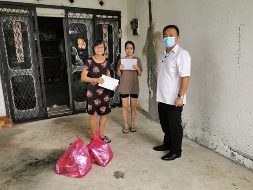 青草路社区发展与治安委员会主席甲必丹陈国璋（右）为其中一户家庭送上新春礼品时影。