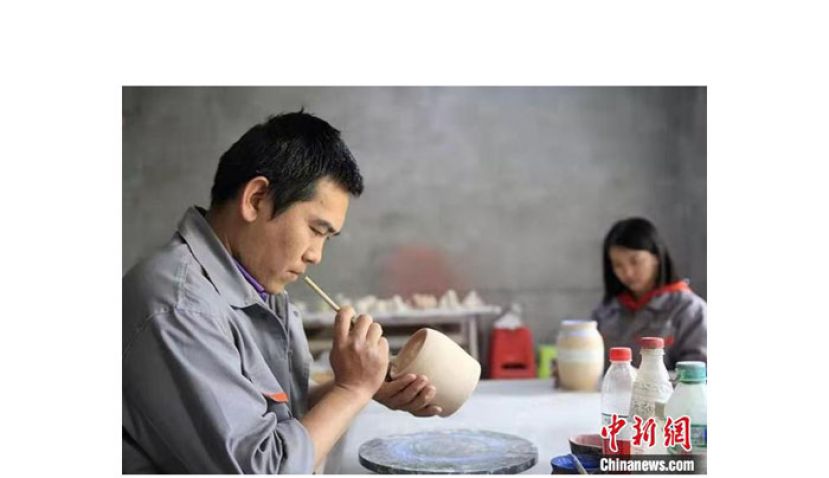 张俊良正在对陶艺产品绘制。