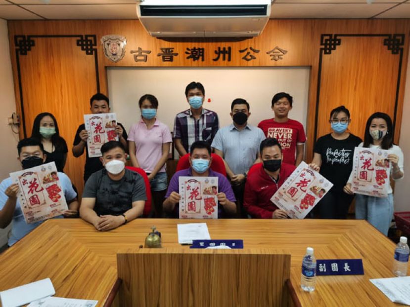 古晋潮州公会青年团团长黄伟忠（坐者左二）带领团委及筹委会成员展示举办2022年"出花园"成人礼之宣传海报。坐者左一为署理团长沈茂前，筹委会主席陈永林（右二）及筹委会副主席卢隆泰（右一）。