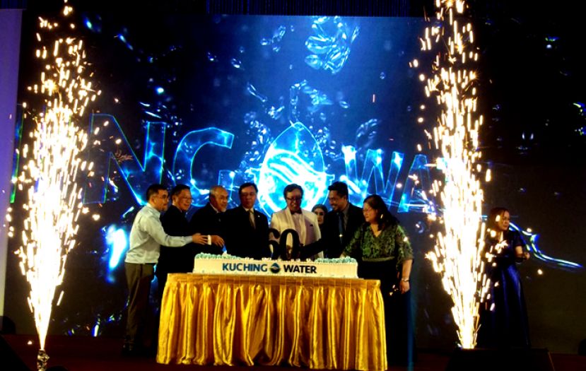  砂首席部长拿督巴丁宜阿邦佐哈里(右三)主持切 60周年庆典蛋糕时摄。后方荧幕显示古晋水务局新徽标。