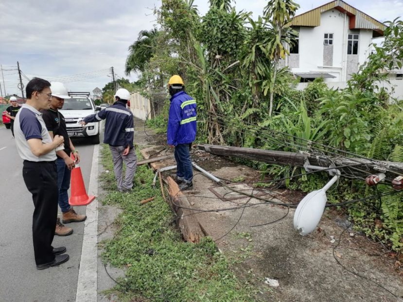 人联党峇都林当支部主席薛华东（左）观看电力局人员维修香蕉路西段倒下电灯柱及电线情况。