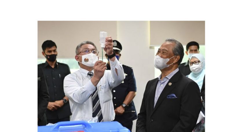 卫长阿汉巴巴向首相展示注射器的使用法。