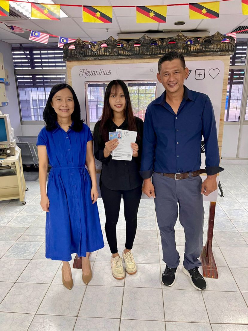 在砂拉越总理政治秘书许德婉(左)协助与陪同下，陈欣洁(中)终获得大马卡身份证。右为陈欣洁父亲陈国祥。