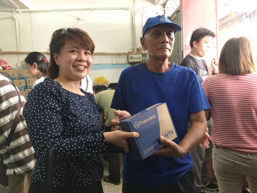 朋岭区州议员杨薇讳（左）派发数码电视解码器予其中一位受惠人士时摄。