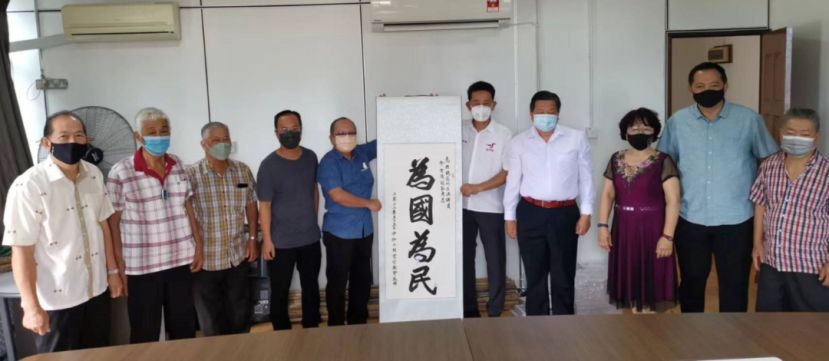 中砂六桂堂宗亲会副会长龚招睷（左5）在主席江宗兴（左7）及理事见证下，赠送&ldquo;为国为民&rdquo;字幅予拿督陈冠勋（左6）。左起为龚招亨、江国逸、甲必丹方书强、翁新达县议员；右起是翁建忠、龚世顺、甲必丹江丽訇。