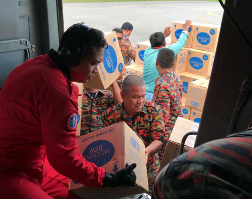 消拯人员在居民们协助下，将矿泉水一箱箱抬下直升机。