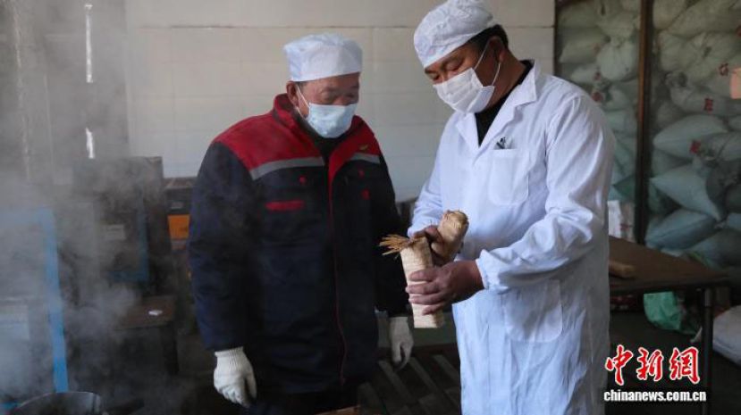 普桃(右)与茶场工人在研究茶叶的竹条包装。