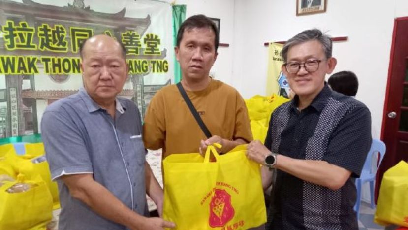 因交通意外事故失去右手臂的沈文杰（中）溢于言表由砂同心善堂主席黄国远（左）及主宾薛华东（右）手中接过布施品。