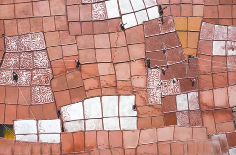 西藏盐田航拍照片，人们正在颜色深浅不一的红色盐田劳作。