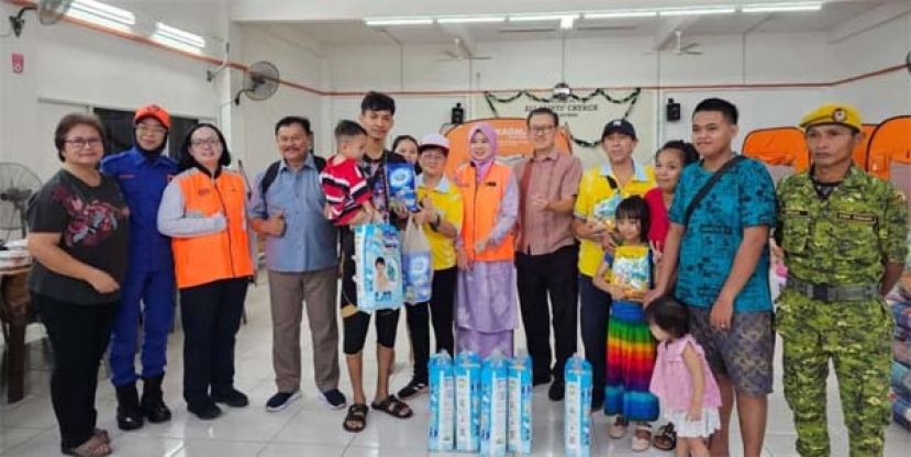 砂同心善堂的代表张淑禧（左6）及陈惠生（左9）在薛华东（左8）见证下移交奶粉给灾民的孩童。