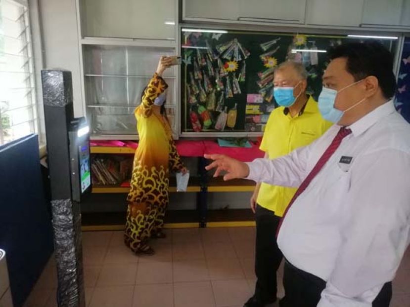 罗东中公校长赖招恬向陈超耀介绍人脸识别温度测试仪。