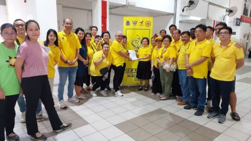 人联党峇都林当支部青年团长黄昭信（中左）将为乐龄民众填写的申请表格移交给支部执行秘书郭小凤。右起为许嘉胜、许义华、市议员雷士、甲必丹陈庆耀，左9是妇女组主任甲必丹何月明、市议员莫壮平（左5）等人。