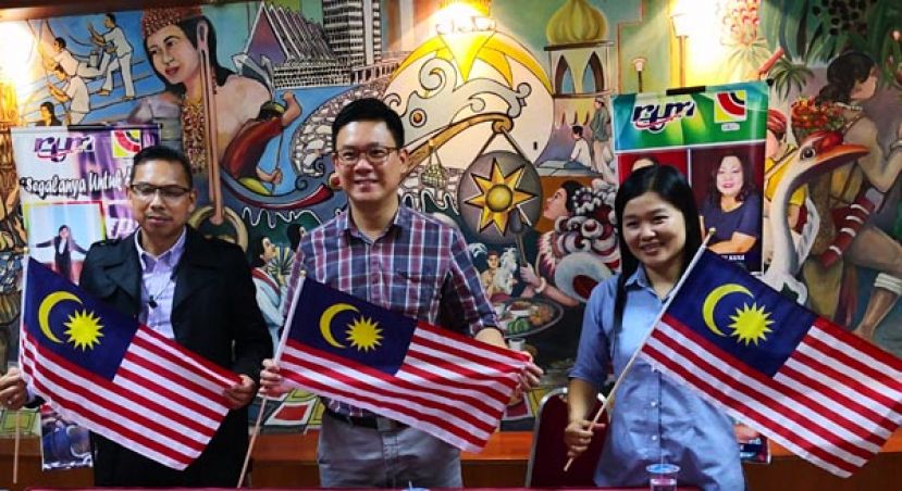 林财耀（中）、诗巫电台经理赛夫宾阿兹尼（左）及诗巫新闻局代表陈淑伶（右）挥舞国旗。