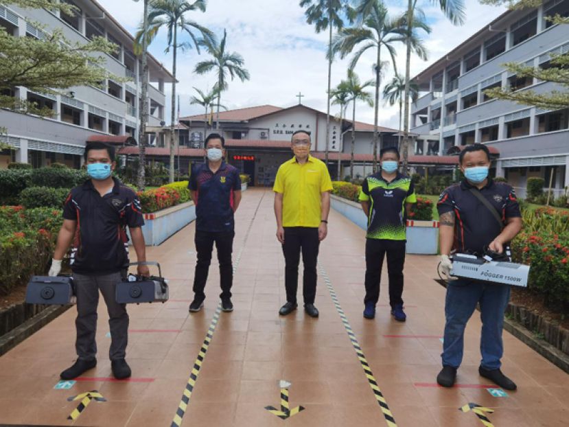 图一：郑摩多专卖店董事郑国栋（右三）率领员工到七哩三合兴小学进行喷雾消毒工作。左二和右二分别是校长黄玉祥和副校长许少贤。