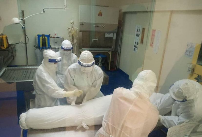 医护人员为穆斯林遗体裹上卡凡白布。