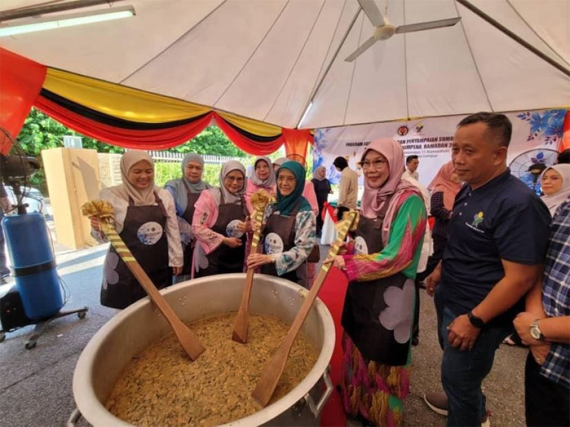 砂拉越总理夫人兼砂公务员福利及体育理事顾问潘斯里拿督阿玛祖玛安妮（右三）烹煮辣粥。