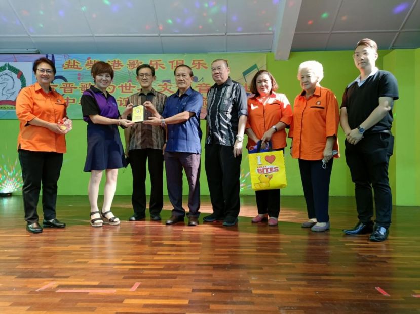 盐柴港歌乐俱乐部负责人甲必丹蔡枂蓉（左起）、古晋歌的世界文娱音乐社梁诗云老师、在主宾薛华东见证下，赠送纪念品予古晋盐材港民众联谊会主席本固鲁严安干；右起为刘龙雨、社群领袖高华明、何月明及拿督贝朝新。