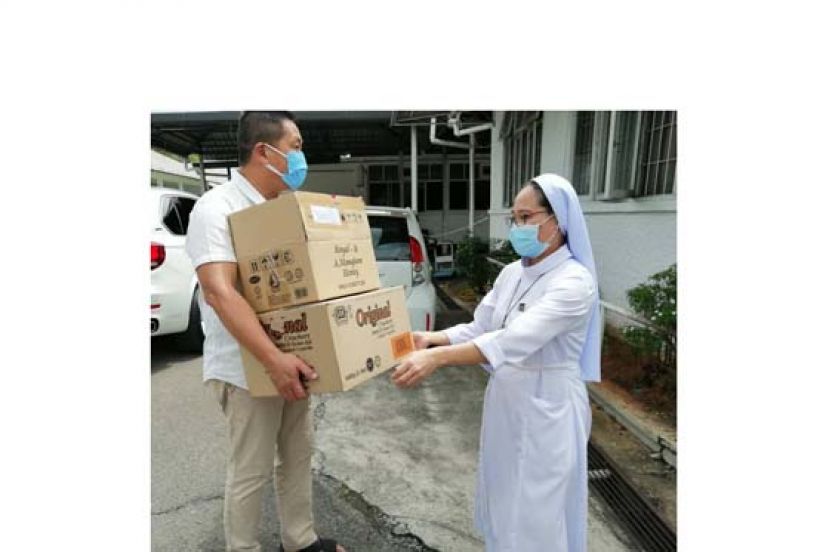施志豪（左）将民众在《爱心工程：网上慈善义卖会》购下的大批食用品，送往指定的砂拉越盲人协会、砂拉越济世之家、砂拉越聋哑协会。