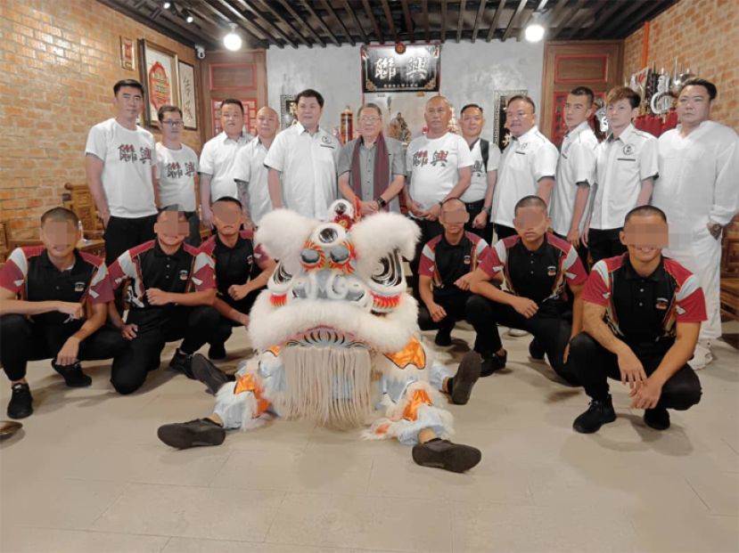 古晋南市市长拿督黄鸿圣（中）与联兴武术协会理事及婆罗洲高原路亨利葛尼少年感化学校舞狮表演团队学员合照留念。