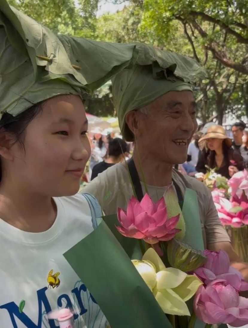  &ldquo;荷花爷爷&rdquo;朱先生（右）与戴荷叶帽的游客。