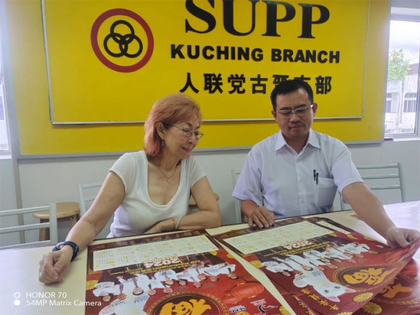 人联党古晋支部主席拿督杨莉（左）及人联党古晋支部副秘书彭大男（右）展示设计精美的月历。