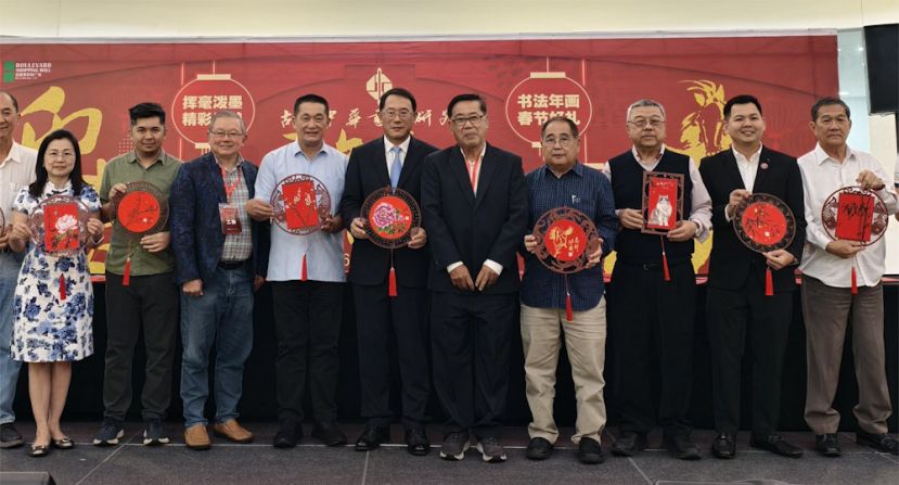 古晋中华书画研究会会长田荣喜（左3）和筹委会主席蔡明卫（右5）赠送书画创作挂饰给主宾施志豪（左4）、中国驻古晋总领事邢伟平（左5）及所有受邀嘉宾。右起为晋汉连省华总秘书长林亚德、古晋中中校友会代表温茹亮、古晋中华书画研究会名誉会长许庆喜、古晋中华书画研究会名誉顾问蔡振强、、柔佛书艺协会署理会长徐华云、富丽华商场首席运营员谢碧霞。