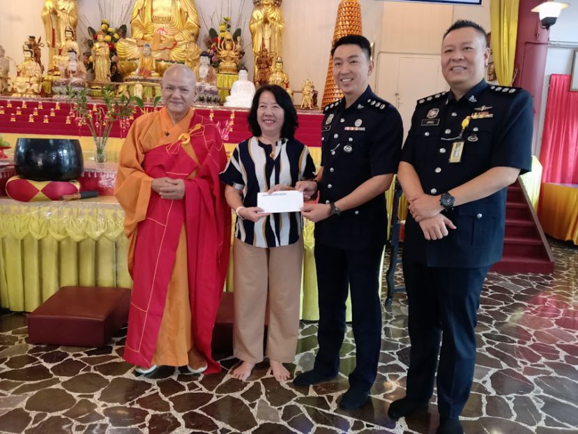 古晋警区刑事罪案调查组代主任陈建国助理警监(右二)代表古晋警察总部移交捐款给予砂拉越佛教会理事会财政房秀芳(左二)作为警察日祈福大会用途。左一为释上日下戒法师；右一为警官林天祥。