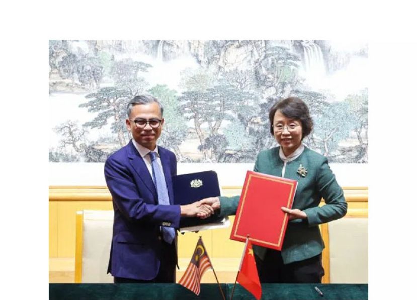 通讯部长法米（左）与曹淑敏交换谅解备忘录。