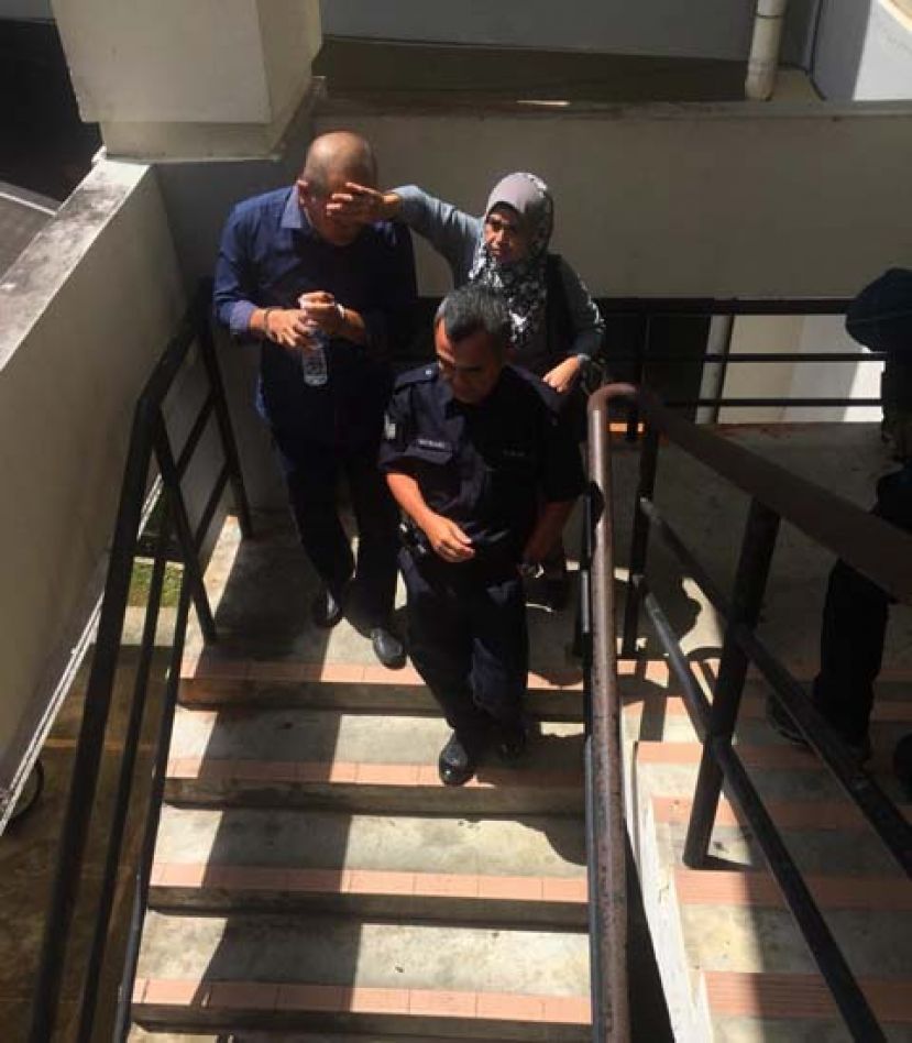 性侵未成年学生罪成的教师被押离法庭时，其太太在一旁忙着为他遮挡镜头。