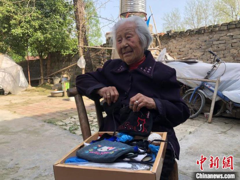 102岁的鞠兰英老人展示自己亲手缝制的零钱袋。