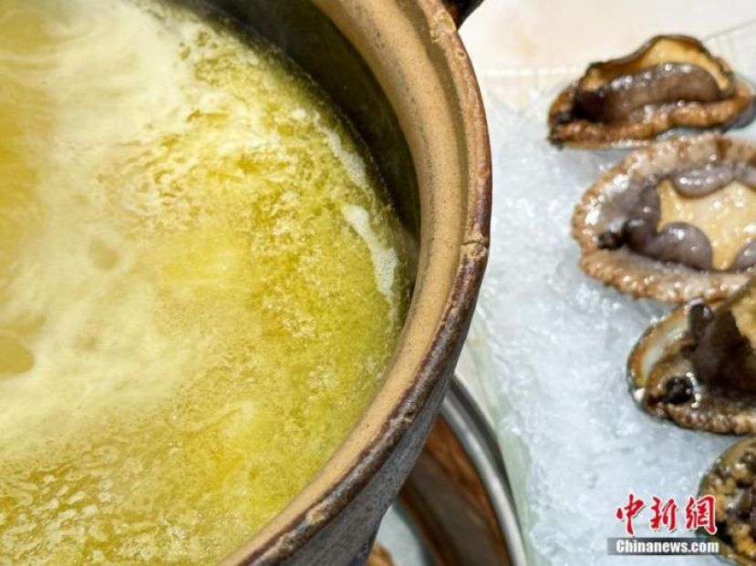 打边炉沸腾的浓汤，散发出诱人的鲜香味，新鲜弹牙的鲍鱼、贝壳等海鲜，令人食欲大增。