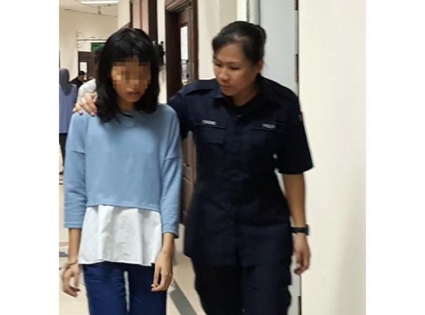 涉嫌以肉刀子砍伤亲生母亲，并将被送往七哩哥打圣淘沙医院接受精神监视的女子（左），被女警押离开法庭时摄。  &nbsp;