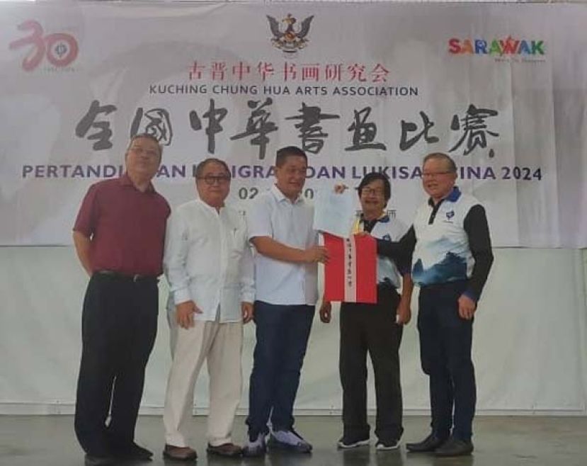 砂拉越巴都林当区州立法议员施志豪（中）为活动主持揭题礼时影。左起为古晋中华书画研究会名誉会长许庆喜、顾问蔡振强；右起为秘书长兼筹委会主席田荣喜以及会长沈捷平。