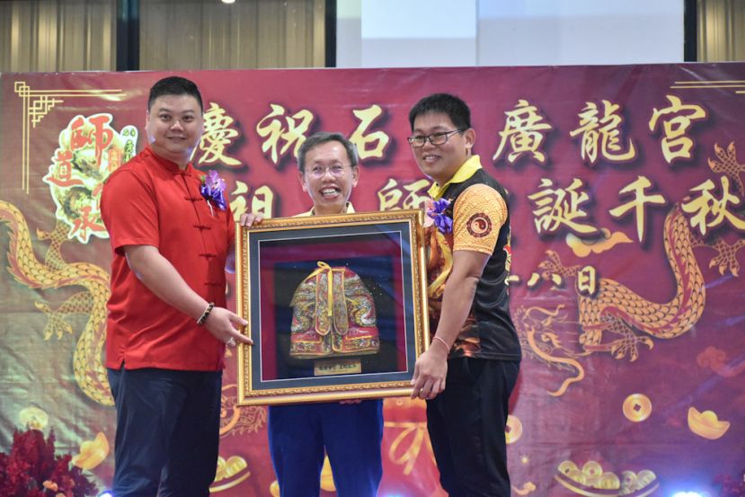 石角广龙宫天师爷公会主席杨胜发（右）与筹委主席谢平豪（左）赠送纪念品予砂副总理拿督阿玛沈桂贤（中）。