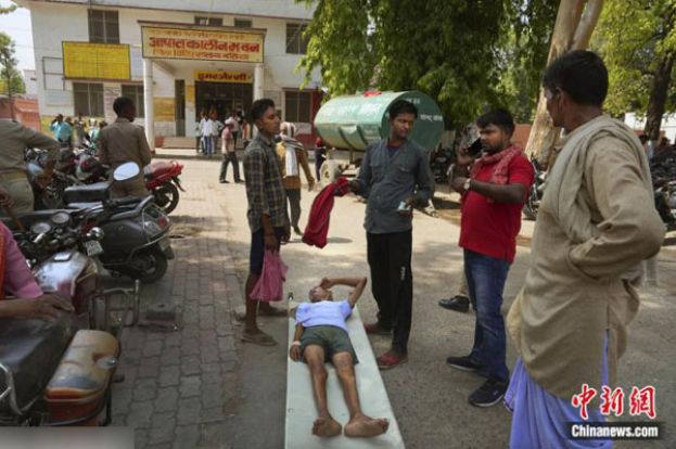 当地时间2023年6月19日，一名中暑的老人躺在担架上在印度北方邦一医院外等待住院。