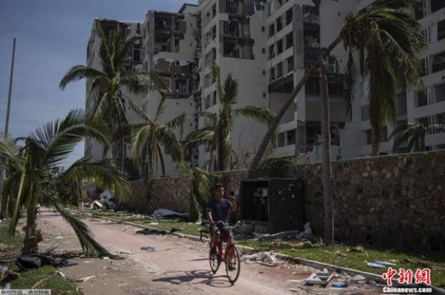10月29日，墨西哥阿卡普尔科，一名男子在受灾地区骑行。