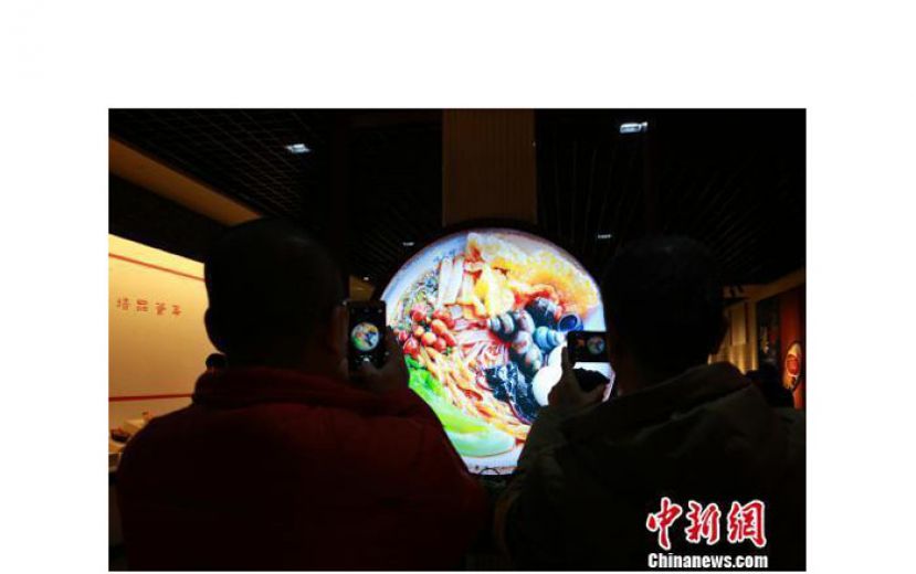 民众用手机拍摄螺蛳粉展示图。